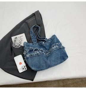 Vue à plat d'un grand sac cabas en denim bleu avec franges et broderie blanche 7THANE