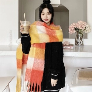 Close-up of soft orange and yellow plaid wool scarf with decorative tassel fringe details
