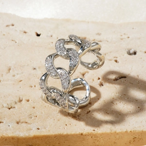 Macro shot of silver paved zircon chain ring on decorative stone texture background