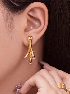 Détail de boucles d'oreilles branche plaquées or 18 carats avec zircons sur le mannequin