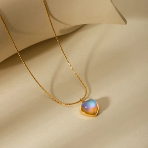 Détail du collier cœur avec pierre de lune aux reflets irisés sur chaîne dorée