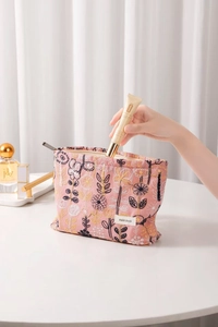 Macro shot of pink makeup bag with detailed floral embroidery and metal zipper closure