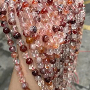 Bracelet en perles de quartz hématoïde rouge naturel présenté à la main en extérieur