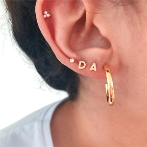 Close-up of S925 silver gold-plated initial earrings and cubic zirconia studs on ear