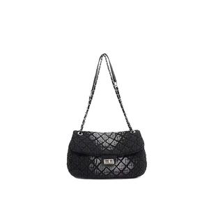 Detailed close-up of black quilted denim fabric and silver chain strap on crossbody bag