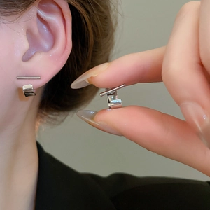 Detailed close-up of a silver T-shaped geometric earring worn on an earlobe