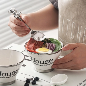 Modern white ceramic bowl with silver rim and cute bear spoon featuring a fresh salad