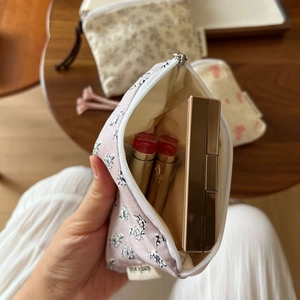 Close-up of a floral canvas pouch storing lipstick on a wooden table setup
