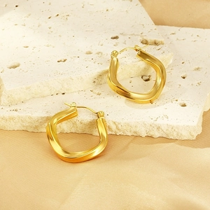 Twisted U-shaped hoop earrings in 18K gold plated stainless steel on silk background