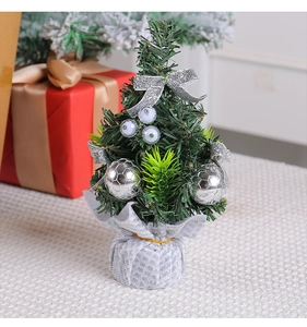 Close-up of mini artificial Christmas tree with silver bows, berries and metallic pot wrap