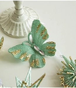 Detail of green butterfly Christmas ornament with gold glitter edges and faux gems