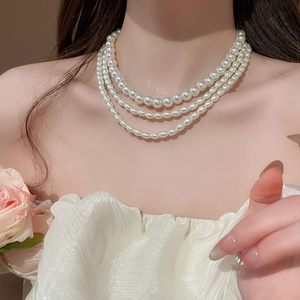 Close-up of triple-layer pearl choker necklace on model featuring elegant vintage style