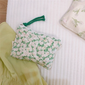 Detailed macro view of green floral fabric mini pouch with green fringe tassel zipper puller