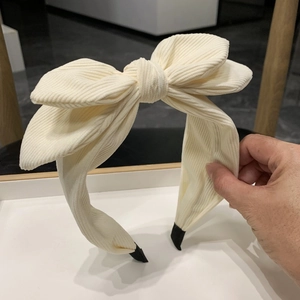 Detail of white corduroy bow headband with wide band design and non-slip protective tips