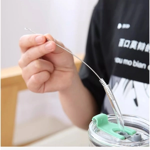 Detailed view of flexible stainless steel brush cleaning a transparent glass straw