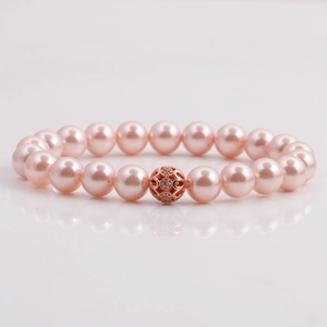 Pink pearl beaded bracelet with rose gold hollow charm on a clean white mirror surface