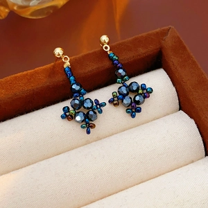 Macro shot of handmade beaded star earrings in a velvet jewelry box display