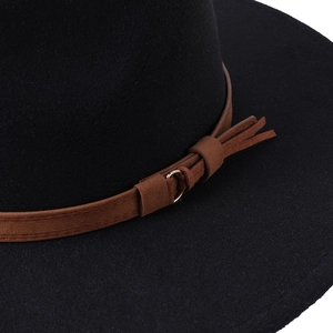 Detail of black felt fedora featuring a brown suede band with metal buckle and fringe