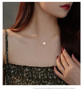 Macro detail of a gold floral necklace with white shell petals and sparkling crystals