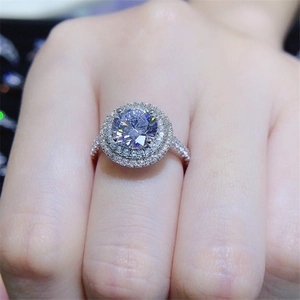 Macro shot of a brilliant round zircon engagement ring with a double halo and pave band