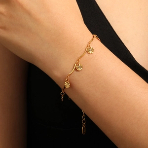 Golden bracelet with three sun-textured charms on a wavy chain worn by a model