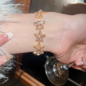 Macro close-up of rose gold five-petal flower bracelet with pink zircon on wrist
