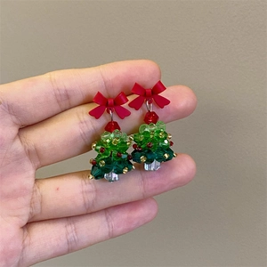 Detailed view of hand-woven beaded Christmas tree earrings with a red bow and green crystals