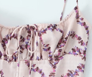 Detail of satin floral dress featuring pleated neckline and lace-up bow decoration
