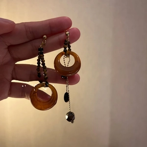 Detailed close-up of vintage resin tiger eye hoop earrings with gold chain pendants