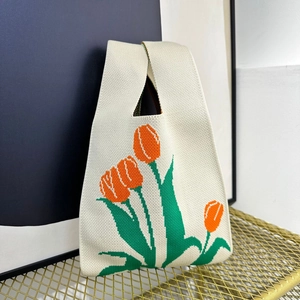 Knitted tote bag with orange tulip pattern and sturdy single handle on a metal stand