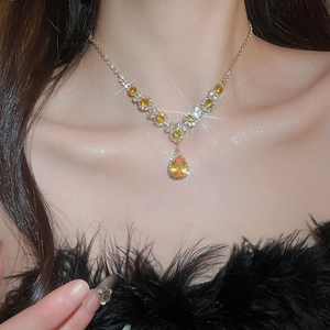 Detailed view of luxury gold necklace with sparkling yellow teardrop zircon crystals on model