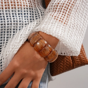 Close-up of amber acrylic chunky bracelet with gold glitter on model's wrist