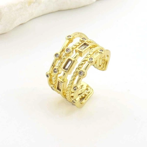 Macro shot of layered gold rope ring featuring square and round zircon stone settings