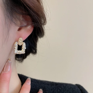 Macro shot of French vintage square pearl earrings with gold texture and crystal detail