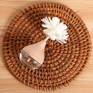Floral reed diffuser bottle with wooden cap on woven mat for home fragrance