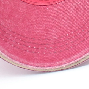 Macro detail of pink washed denim baseball cap brim with four rows of reinforced stitching