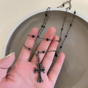 Gothic style double layered cross necklace with black stones in a hand-held view