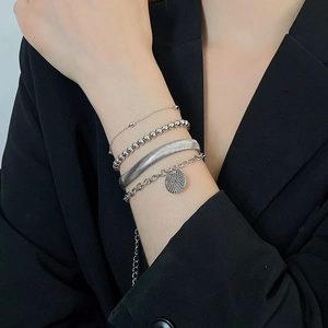 Dettaglio del set di bracciali a catena serpente d'argento e ciondolo tondo sul polso
