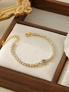 Detail of gold tennis bracelet featuring purple gemstone and white zircon stones