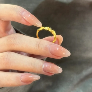 Macro detail of gold plated twisted ring showing matte and polished texture on model hand