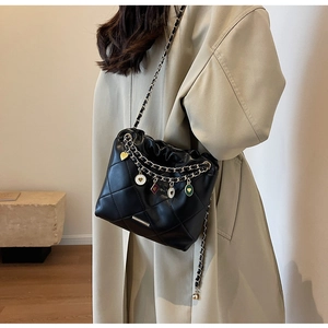 Detail view of quilted chain bucket bag with heart charms and metal hardware
