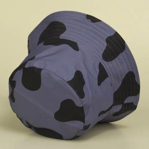 Détail d'un bob violet à motif vache avec taches noires et texture en tissu imperméable