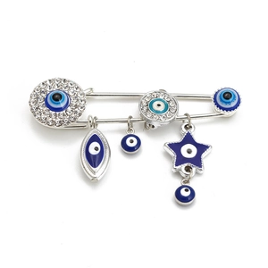 Detailed view of evil eye charms on silver safety pin with blue enamel and rhinestones
