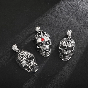 Detailed view of three silver skull pendants featuring crystal and crown embellishments