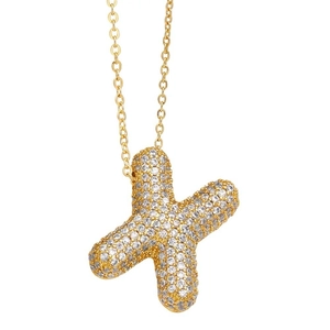 Detailed shot of X-shaped gold pendant necklace with shimmering clear pave-set gemstones