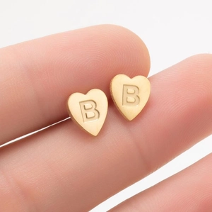 Vue détaillée d'une boucle d'oreille cœur dorée avec un motif de lettre B en relief