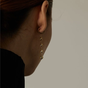 Close-up of gold drop earrings with five sparkling crystals worn by a model