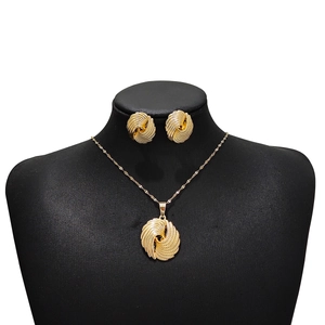Detail of gold swirl shell design necklace and earrings set on a black bust mannequin