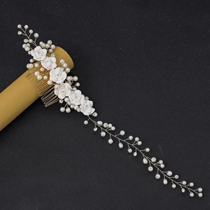 Detail of bridal hair comb with white ceramic flowers, pearls and long gold tassels