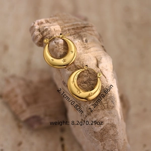 Macro shot of gold crescent moon earrings with star pattern and detailed size dimensions